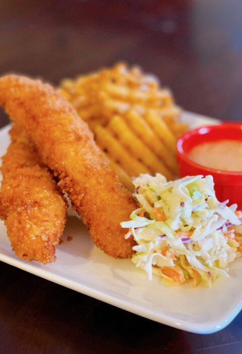 Photo of fried chicken with Cole slaw, waffle fries and sauce to illustrate Raising Canes Chicken Fingers Recipe