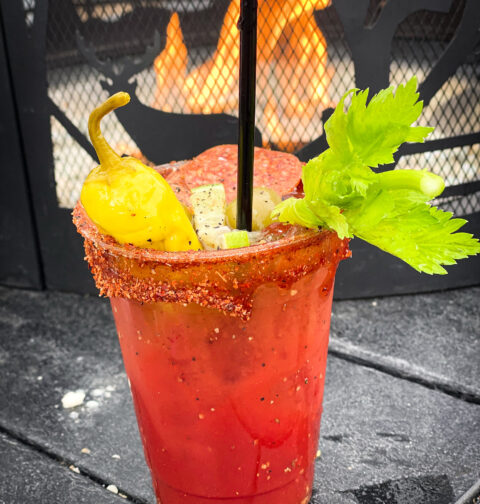 Bloody Mary recipe with celery, pepperoni and pepperoncinis by the fire.