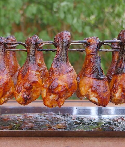Photo of the best smoked chicken legs recipe you'll ever try, made with a peach whiskey BBQ sauce