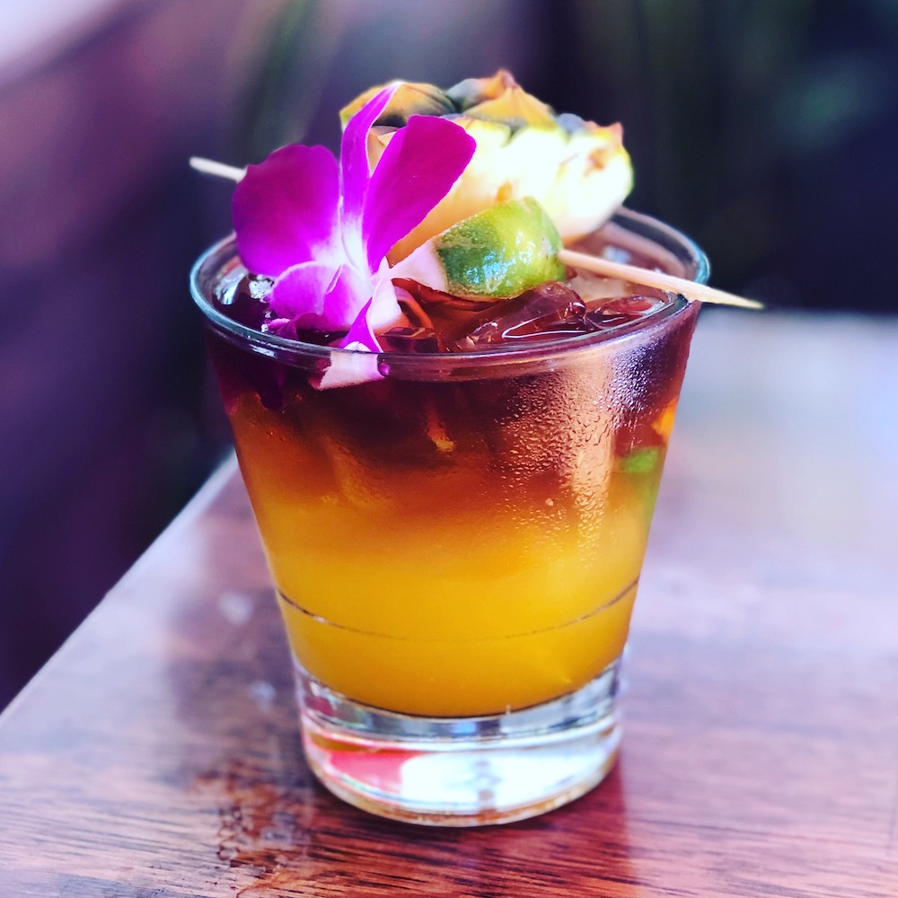 Photo of the best Mai Tai Recipe made with fresh lime juice, light and dark rum, and garnished with a pineapple wedge and orchid.